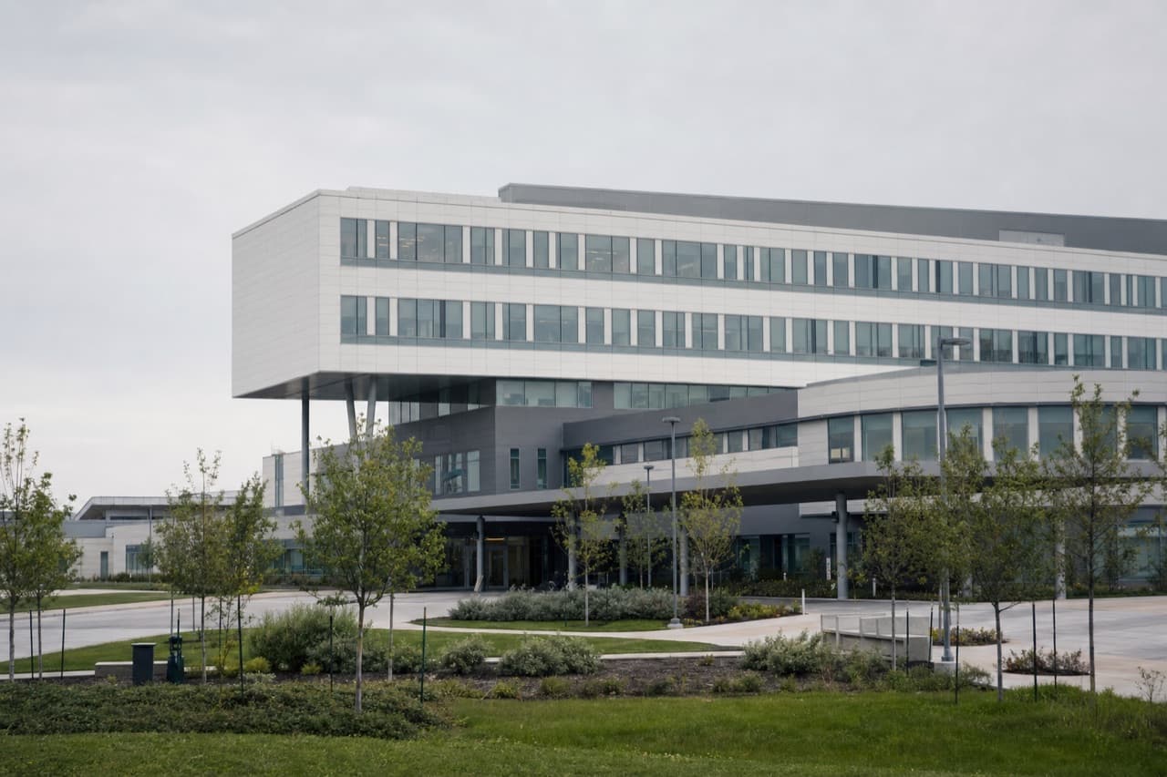 The facade of a contemporary hospital seen across a landscaped forecourt in daylight.